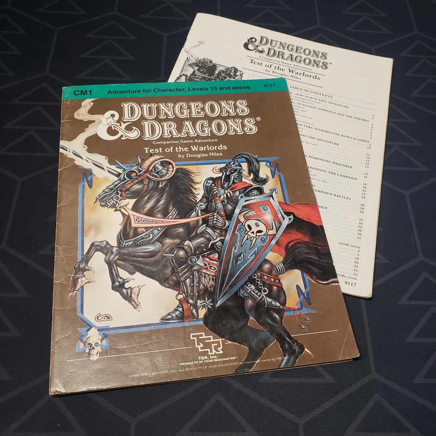 Image shows the front cover of the folio for the Test of the Warlords adventure module for the roleplaying game Dungeons & Dragons 1E with the booklet fanned out