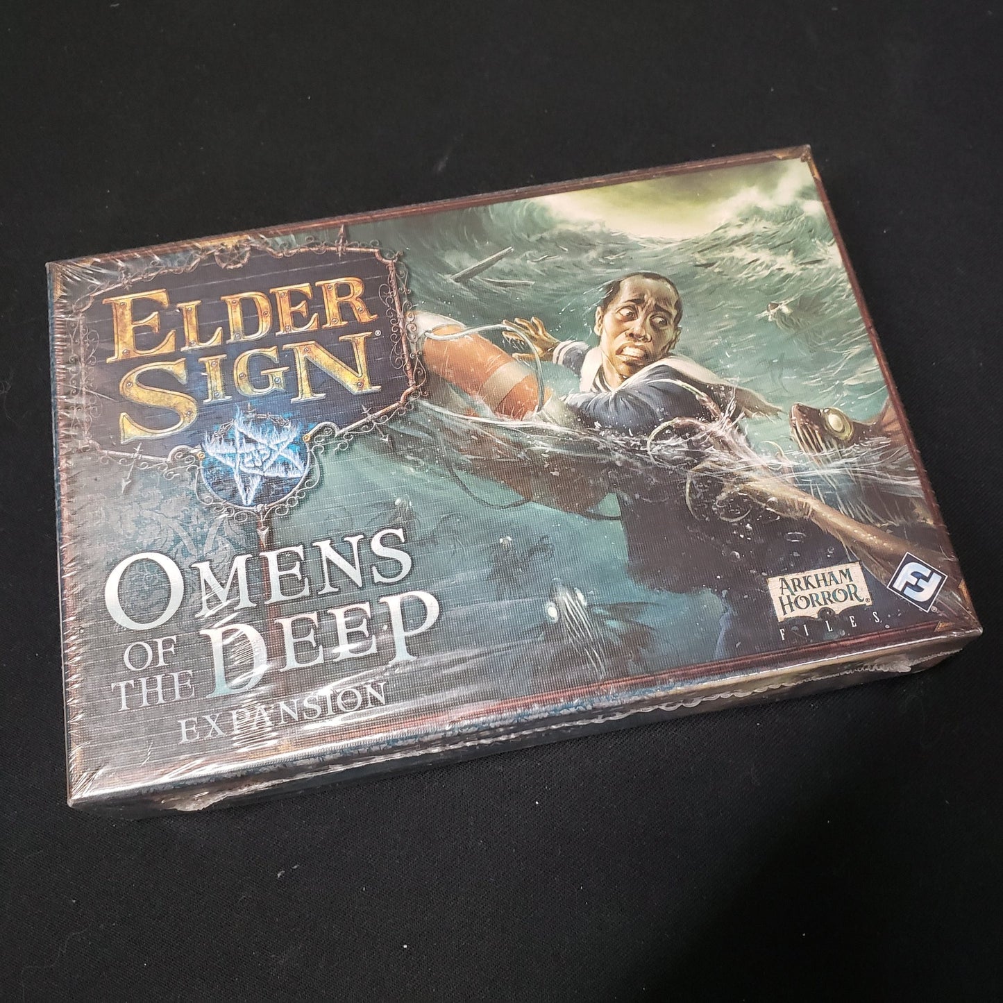 Image shows the front cover of the box for the Omens of the Deep expansion from the board game Elder Sign