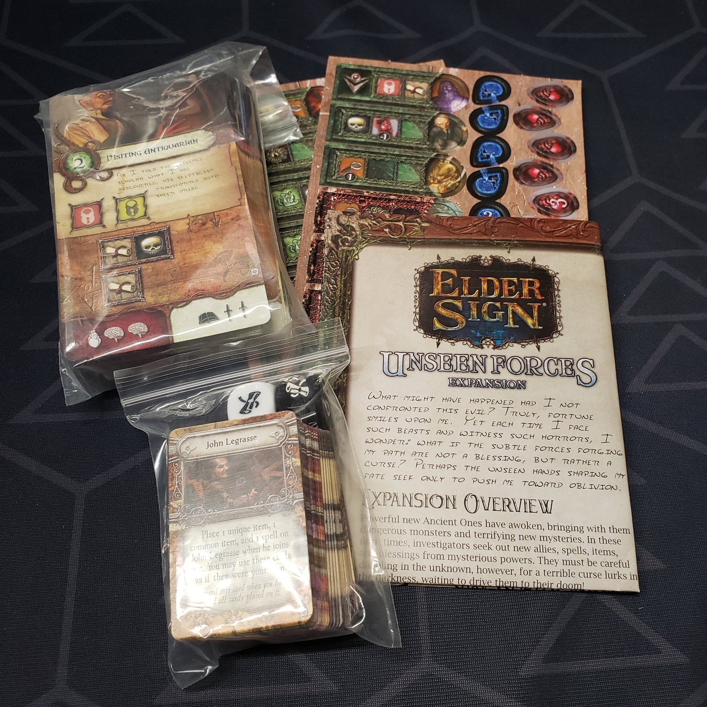 Image shows the instructions and fanned-out components for the Unseen Forces expansion from the board game Elder Sign