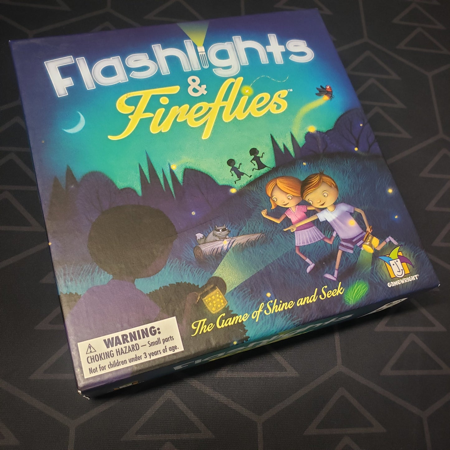Image shows the front cover of the box for the Flashlights & Fireflies board game