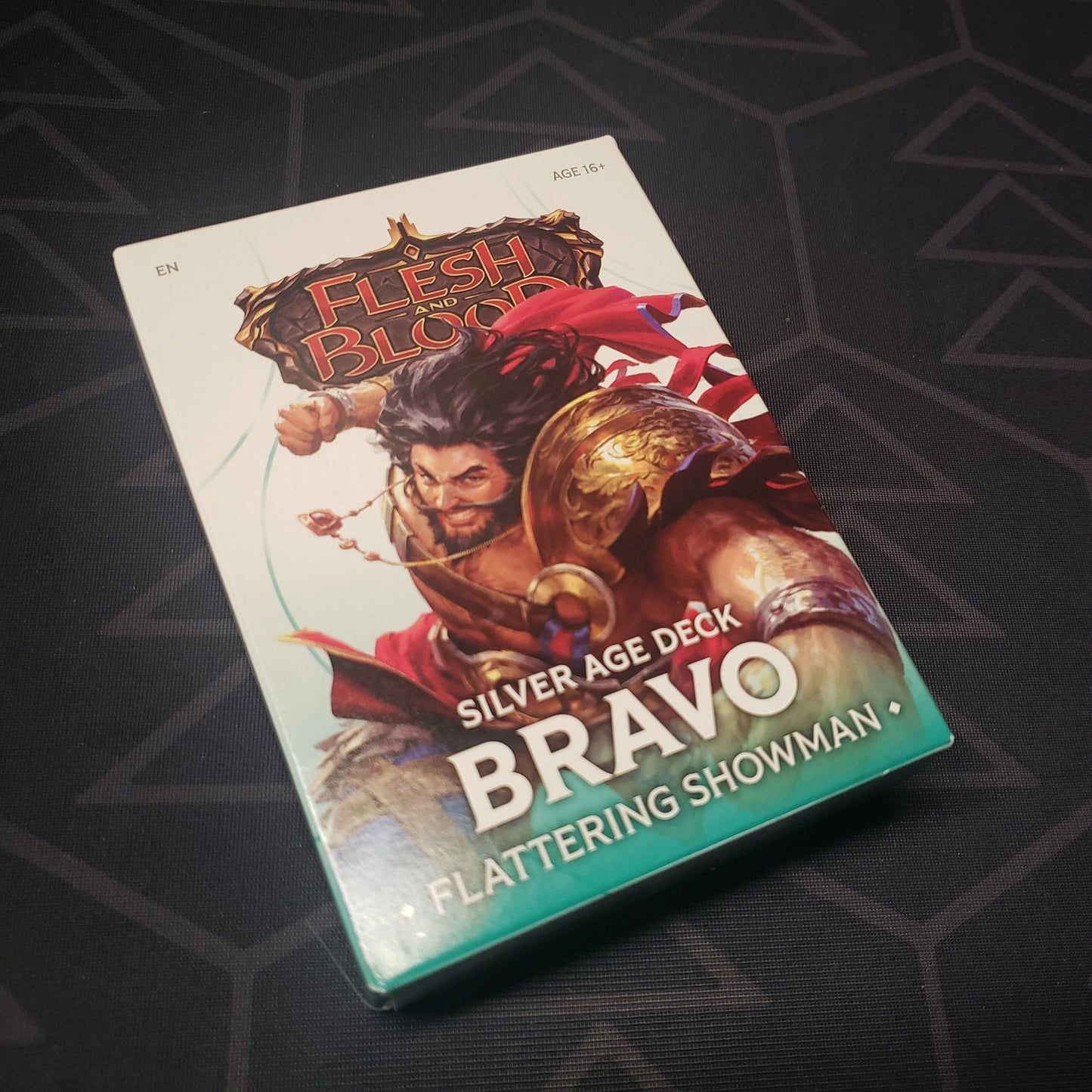 Image shows the front cover of the box of the Silver Age: Bravo, Flattering Showman deck for the card game Flesh & Blood