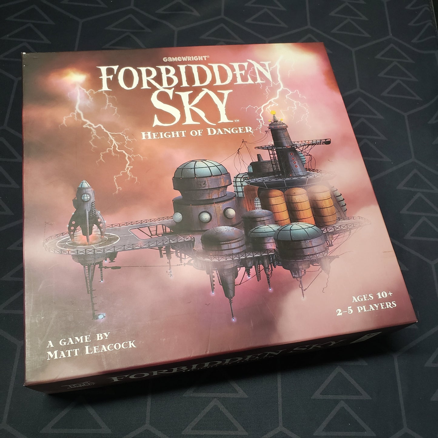 Image shows the front cover of the box of the Forbidden Sky board game