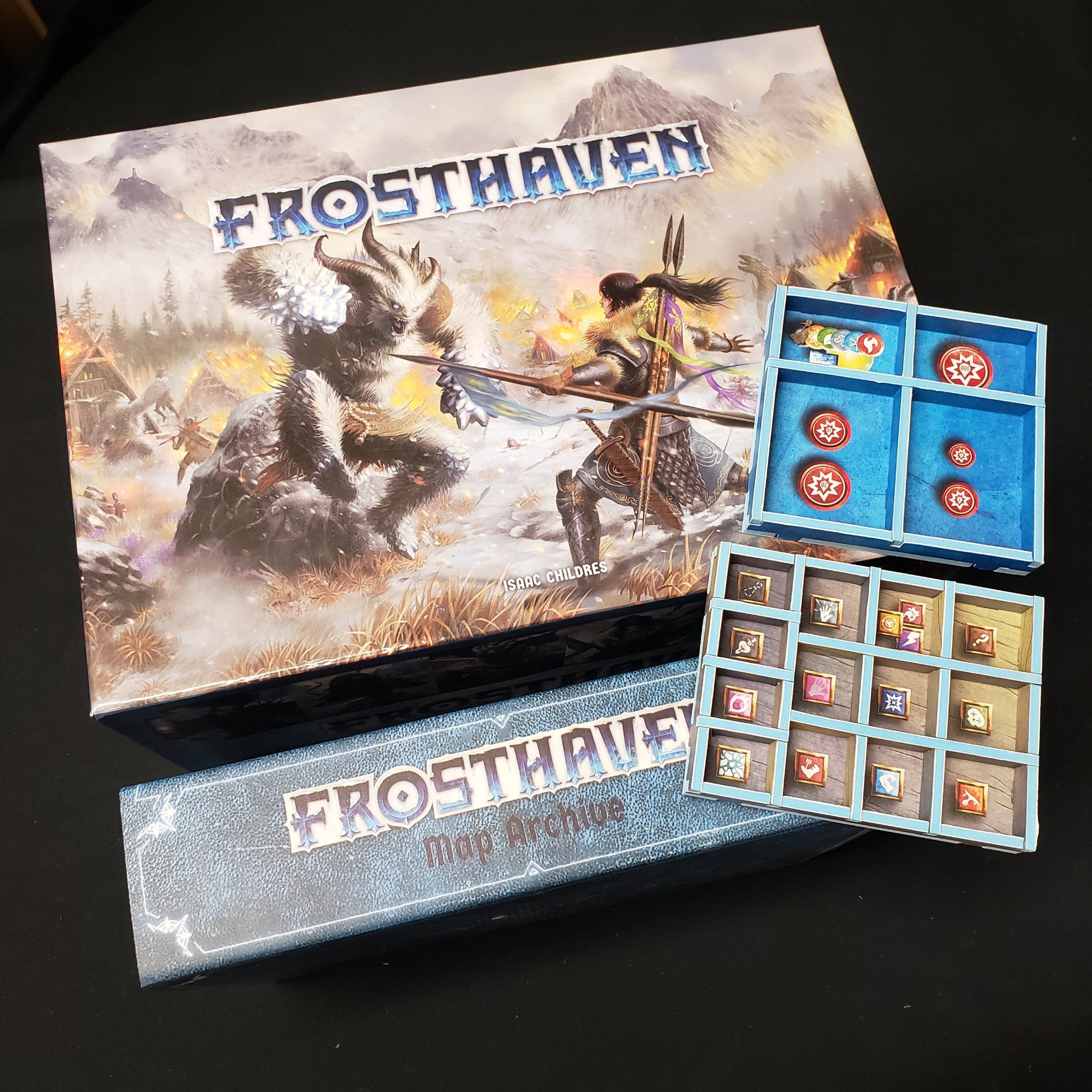 Image shows the top of the box of the Frosthaven board game, along with some hard foam organizers and the op of the Map Archive flexfile