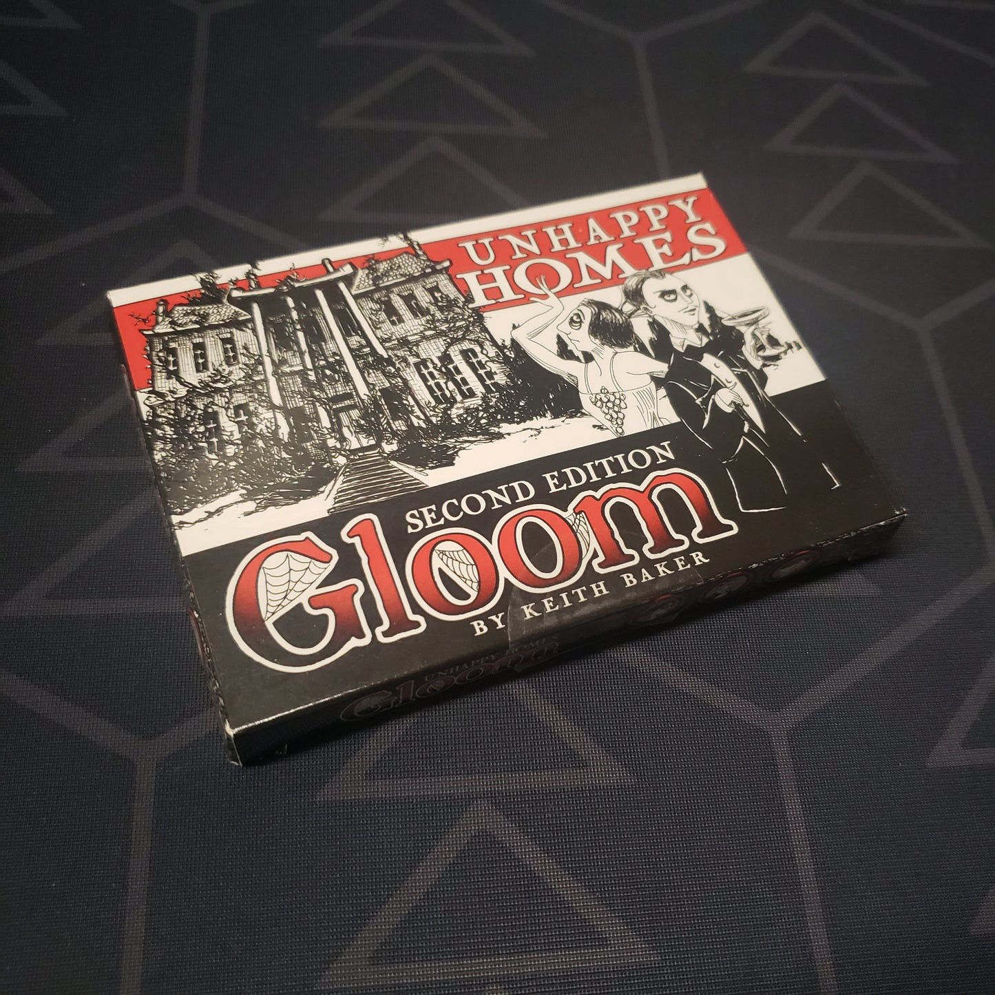 Image shows the front cover of the box of the Unhappy Homes expansion for the card game Gloom (Second Edition)