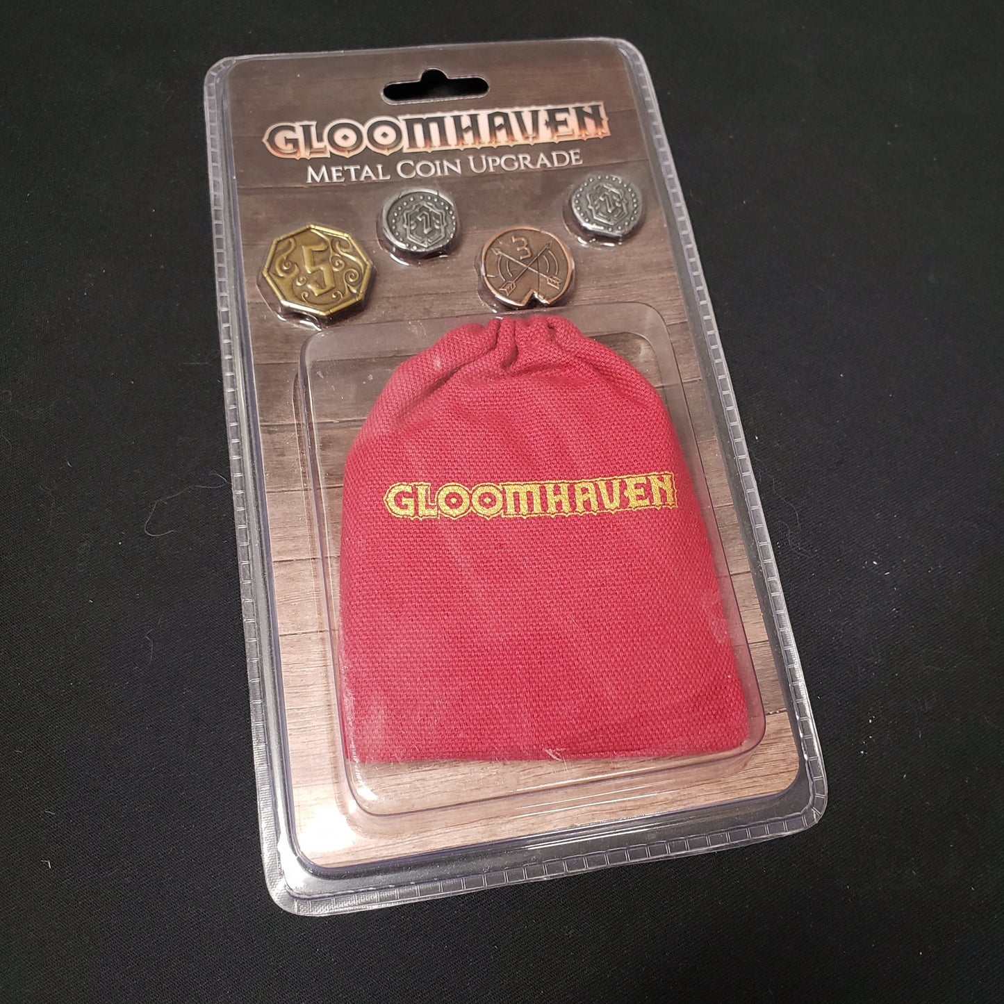 Image shows the front of the package for the metal Coin Upgrad from the board game Gloomhaven