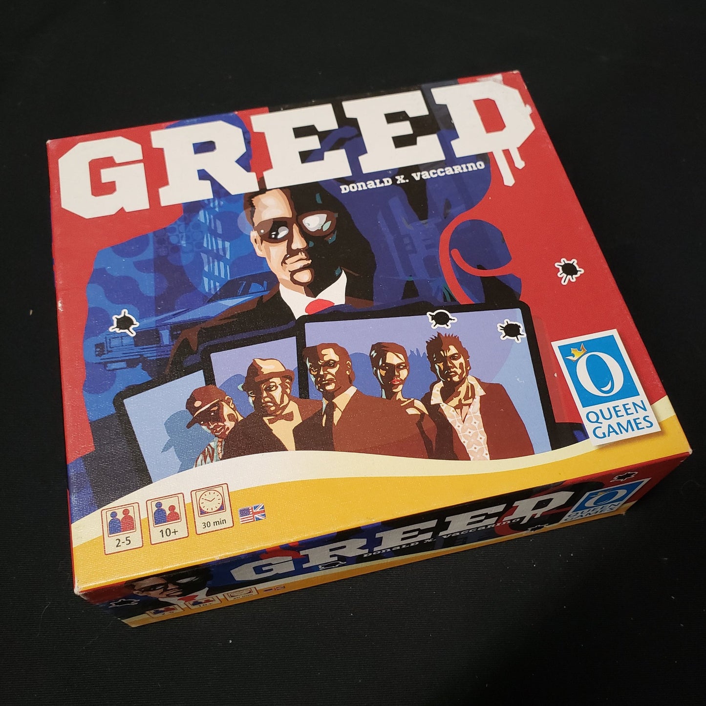 Image shows the front cover of the box of the Greed card game