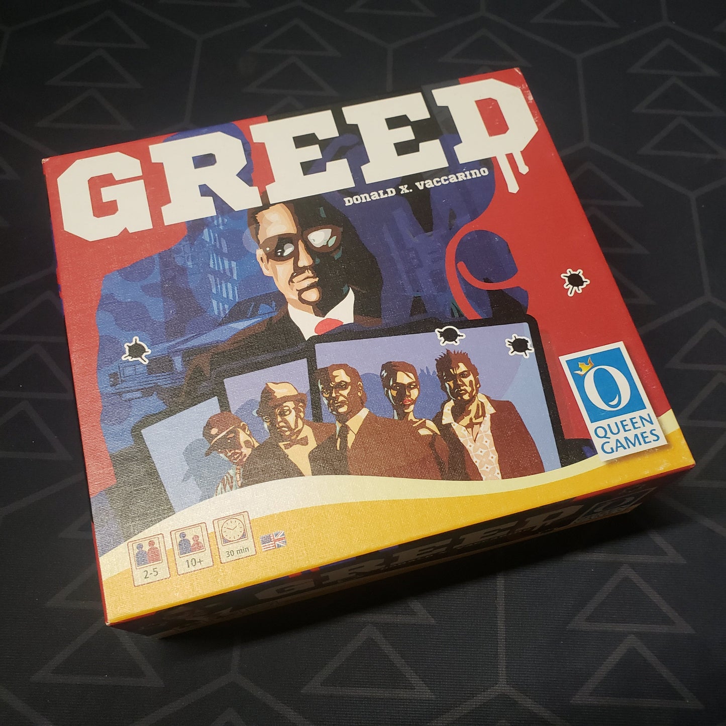 Image shows the front cover of the box of the Greed card game