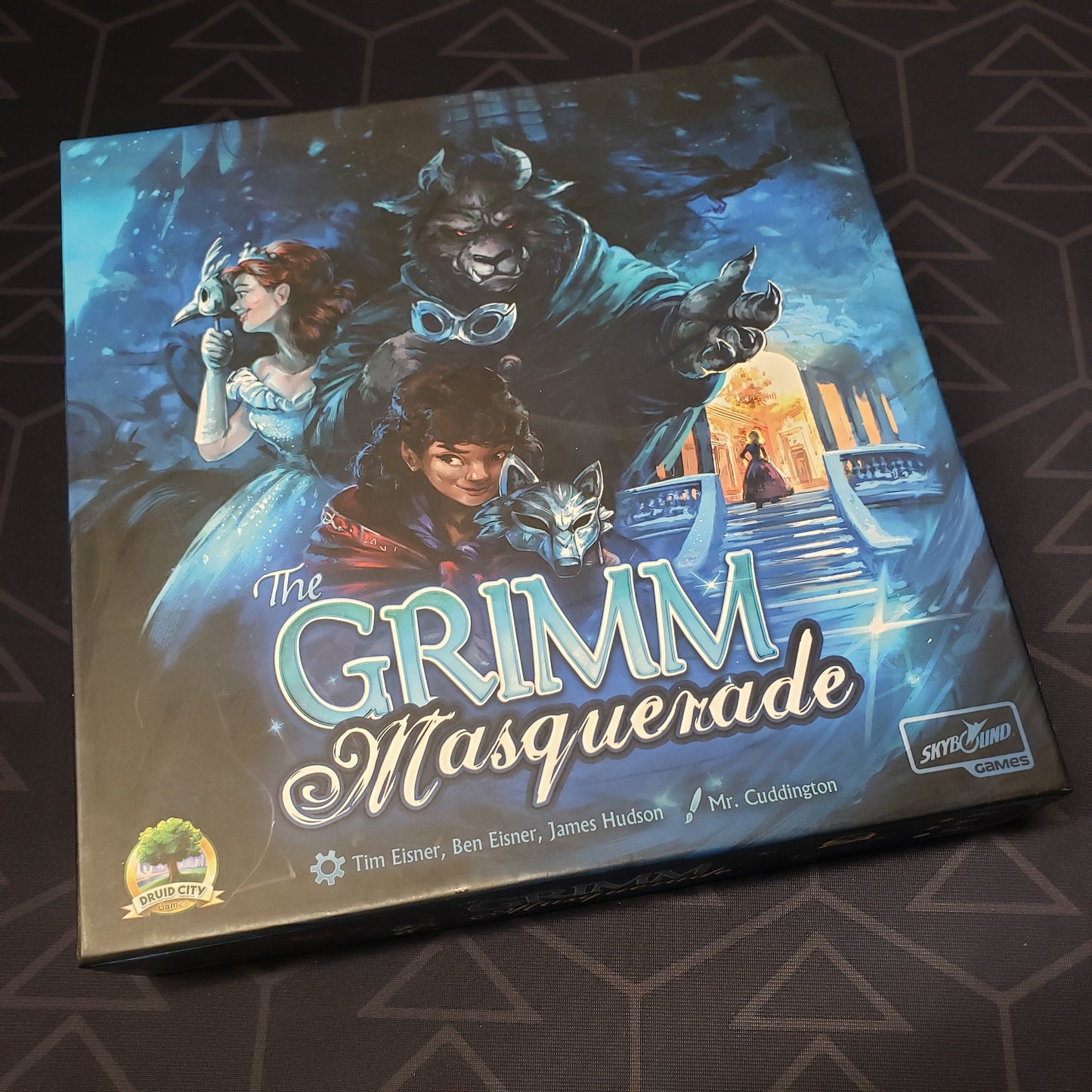 Image shows the front cover of the box of the Grimm Masquerade board game