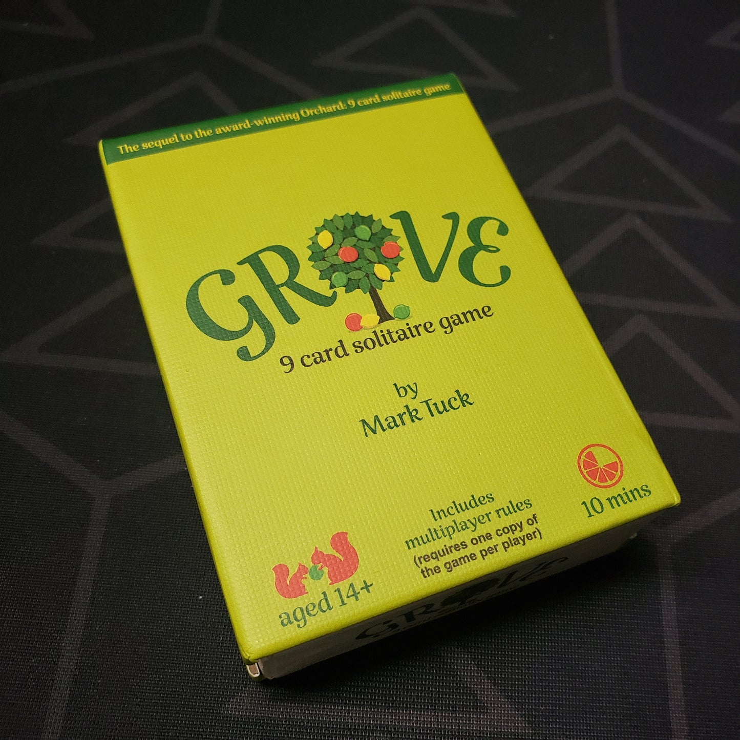 Image shows the front cover of the box for the card game Grove: A 9-Card Solitaire Game