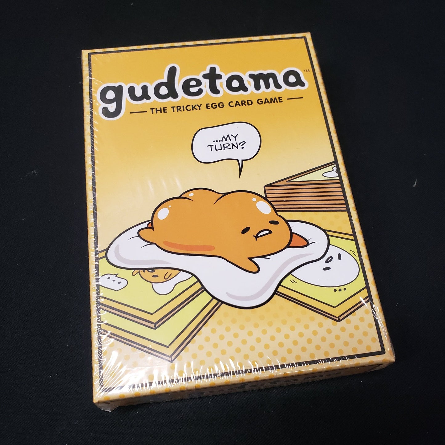 Image shows the front cover of the box of the Gudetama card game