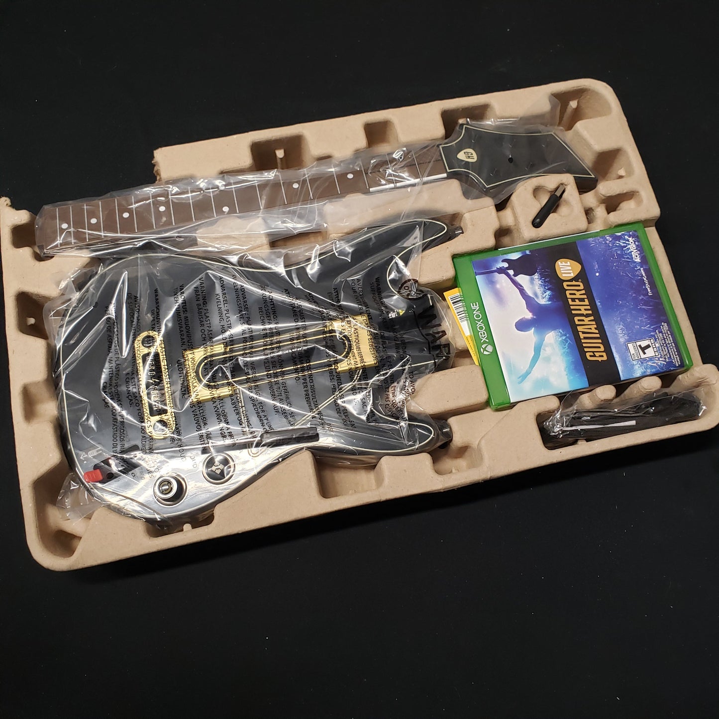 Image shows the contents still in plastic from the guitar bundle box for the video game Guitar Hero Live for Xbox One