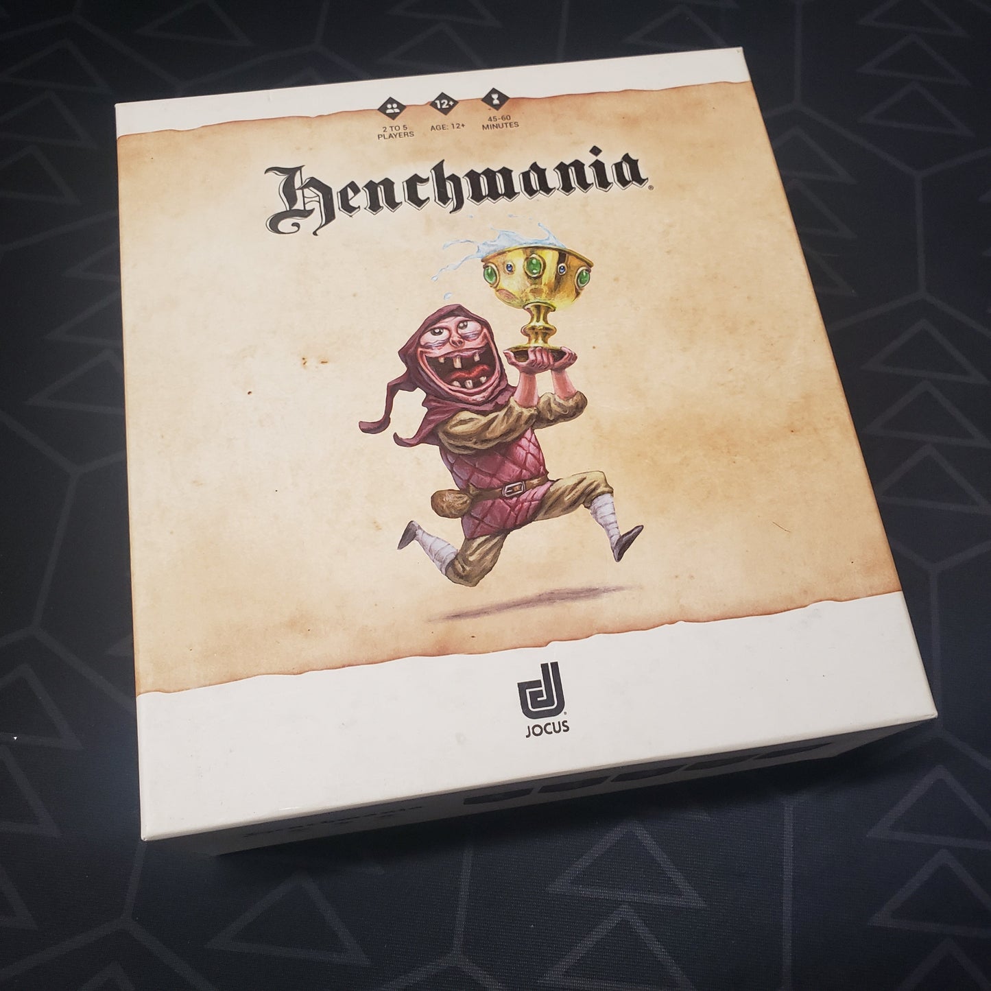 Image shows the front cover of the box for the Henchmania card game