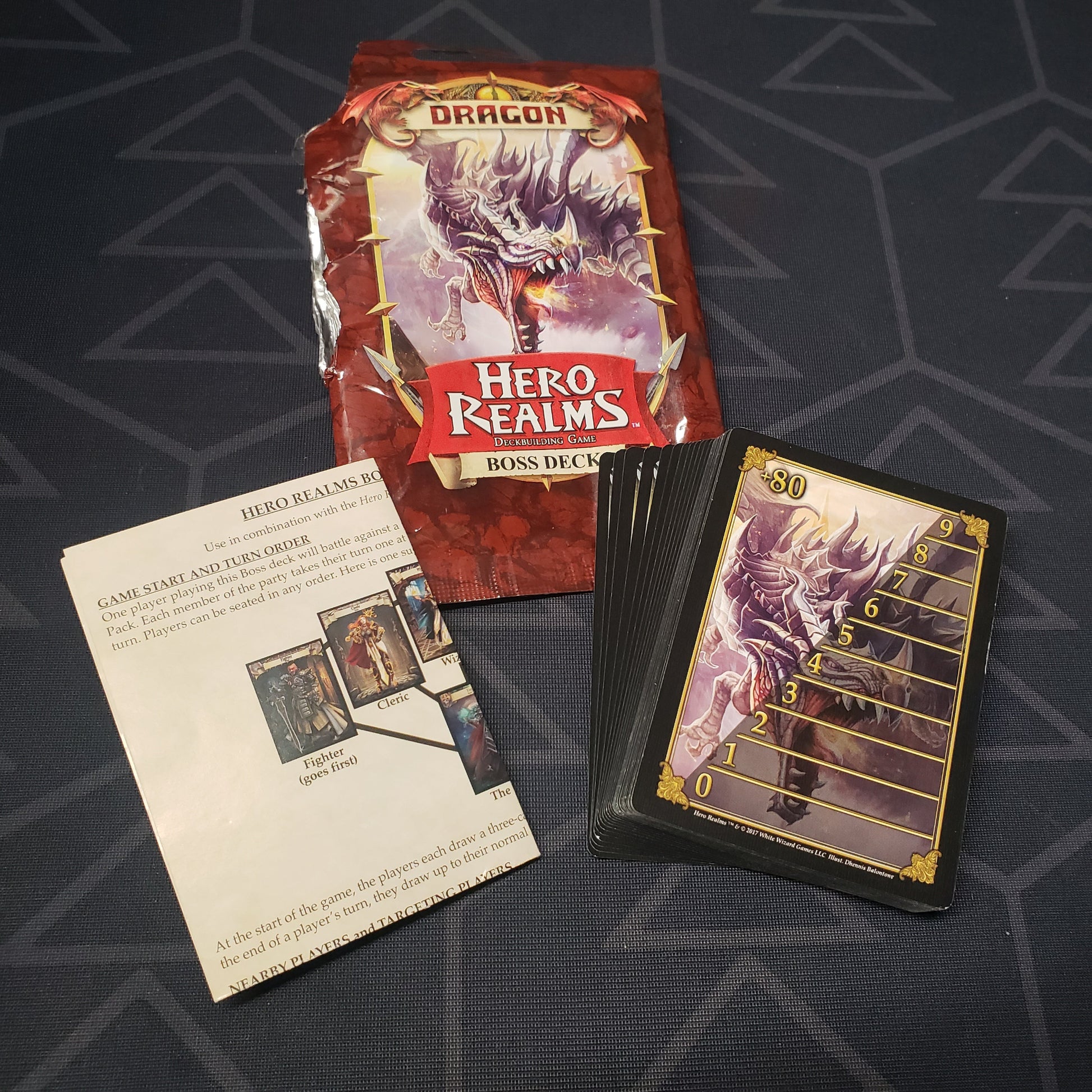 Image shows the foil packaging with the cards fanned out for the Dragon Boss Deck expansion for the card game Hero Realms