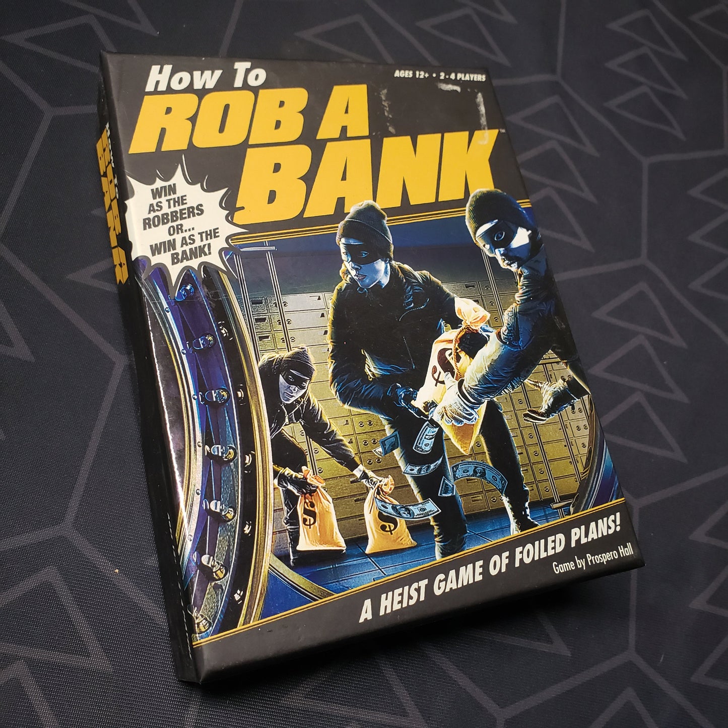Image shows the front cover of the box of the How to Rob a Bank card game