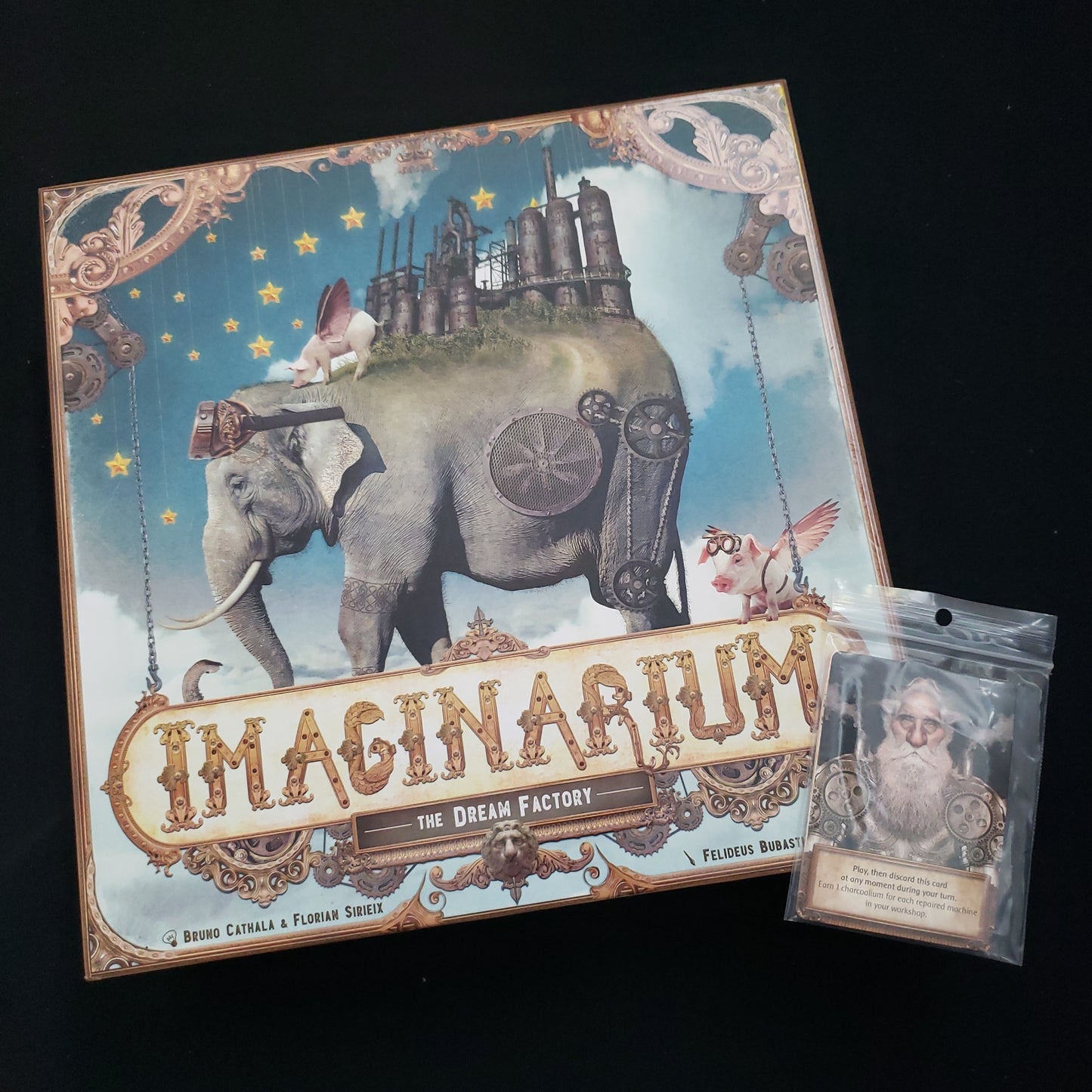Image shows the front cover of the box of the Imaginarium board game, with a promo pack of cards sitting on top of it