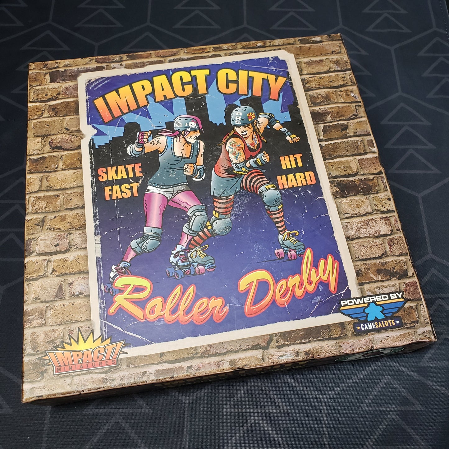 Image shows the front cover of the box for the Impact City Roller Derby board game
