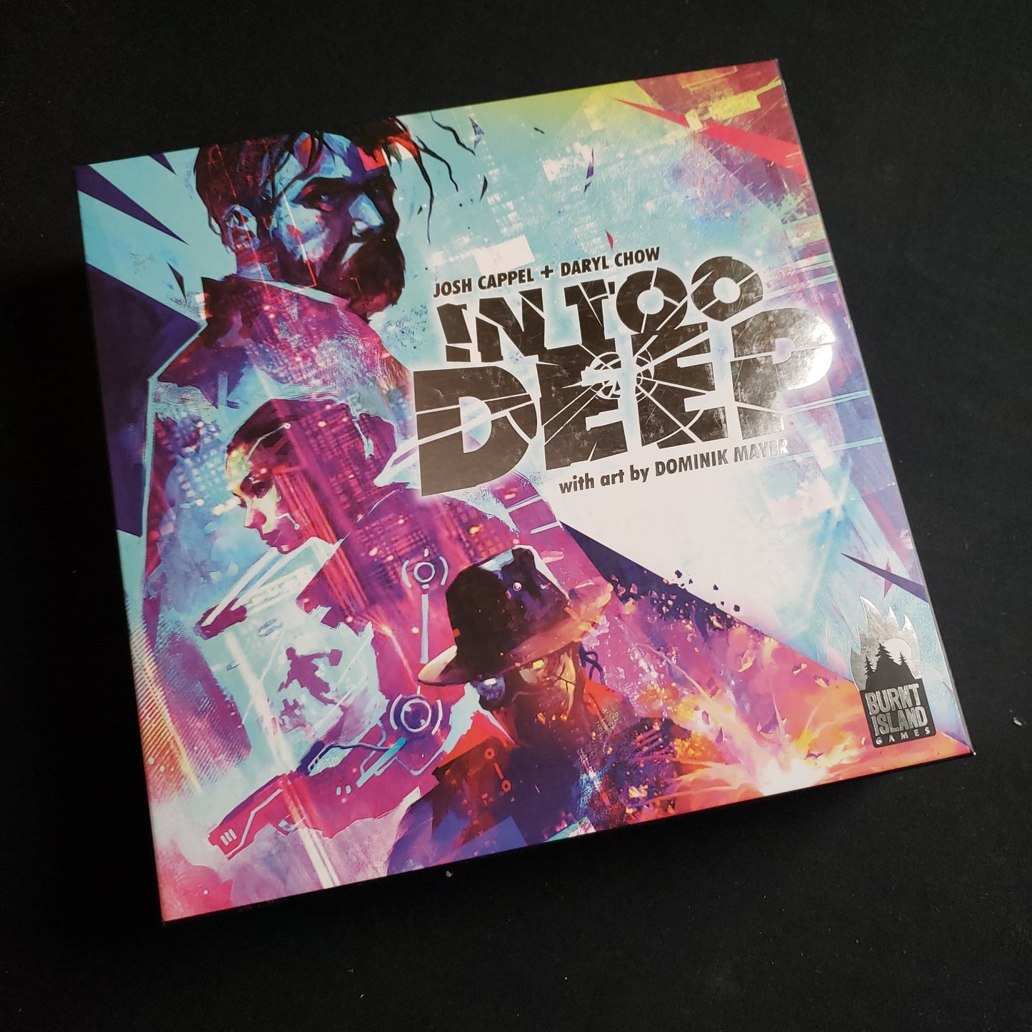 Image shows the front cover of the box of the In Too Deep board game