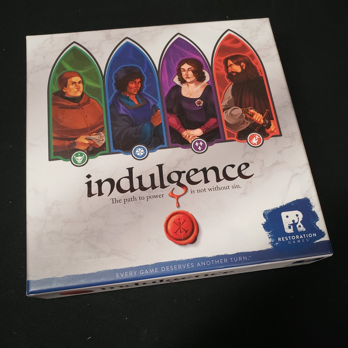Image shows the front cover of the box of the Indulgence card game
