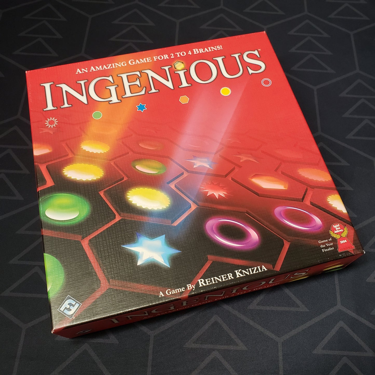 Image shows the front cover of the box of the Ingenious board game