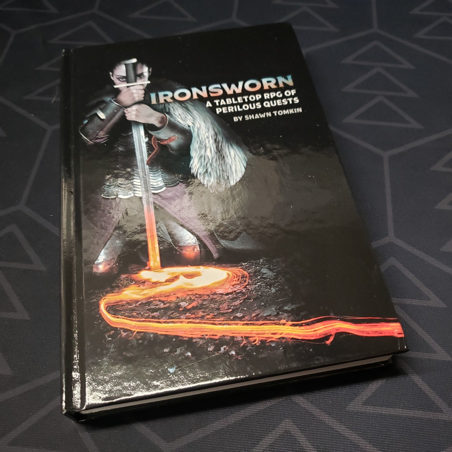 Image shows the front cover of the core rulebook for the roleplaying game Ironsworn