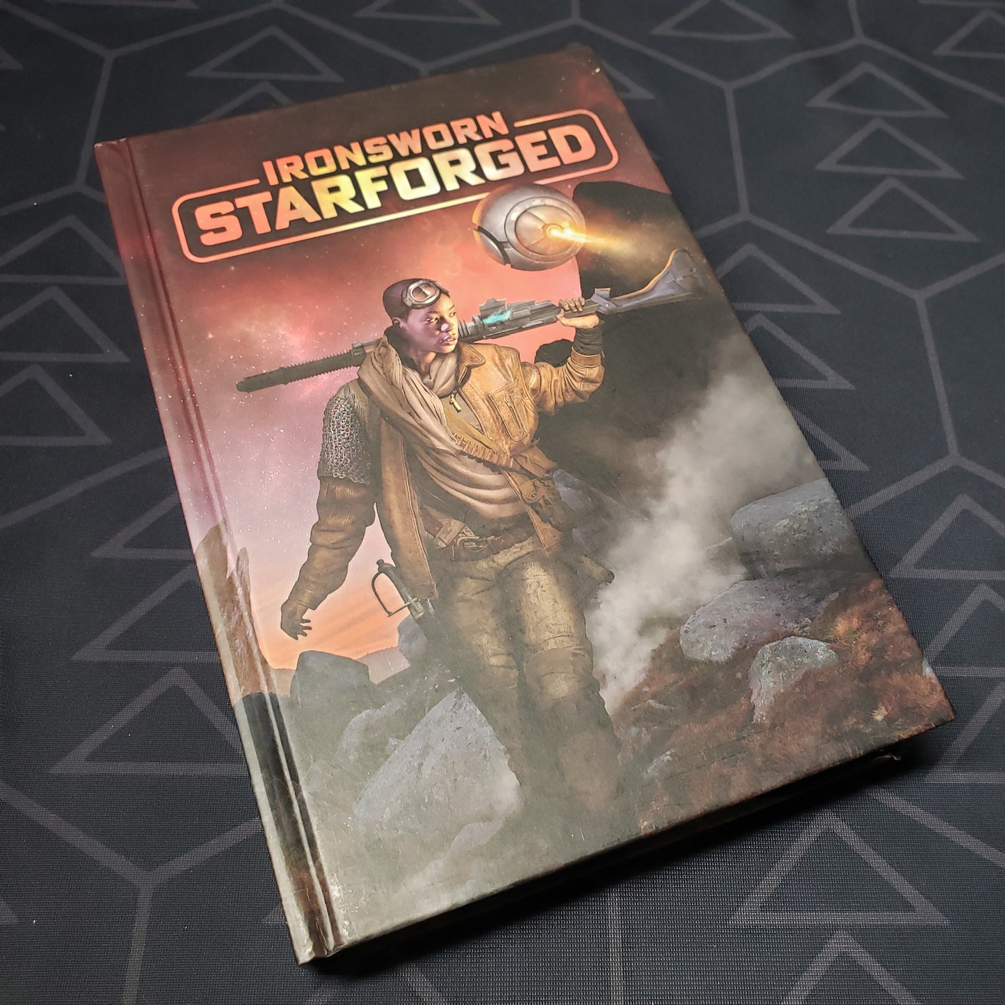 Image shows the front cover of the core rulebook for the roleplaying game Ironsworn: Starforged
