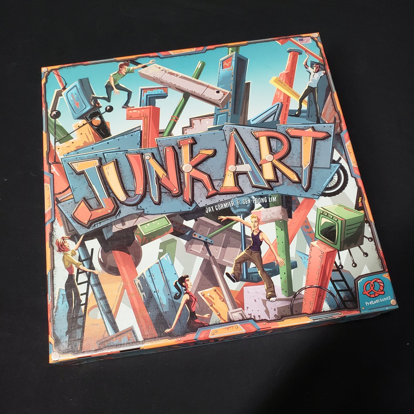 Image shows the front cover of the box of the Junk Art board game
