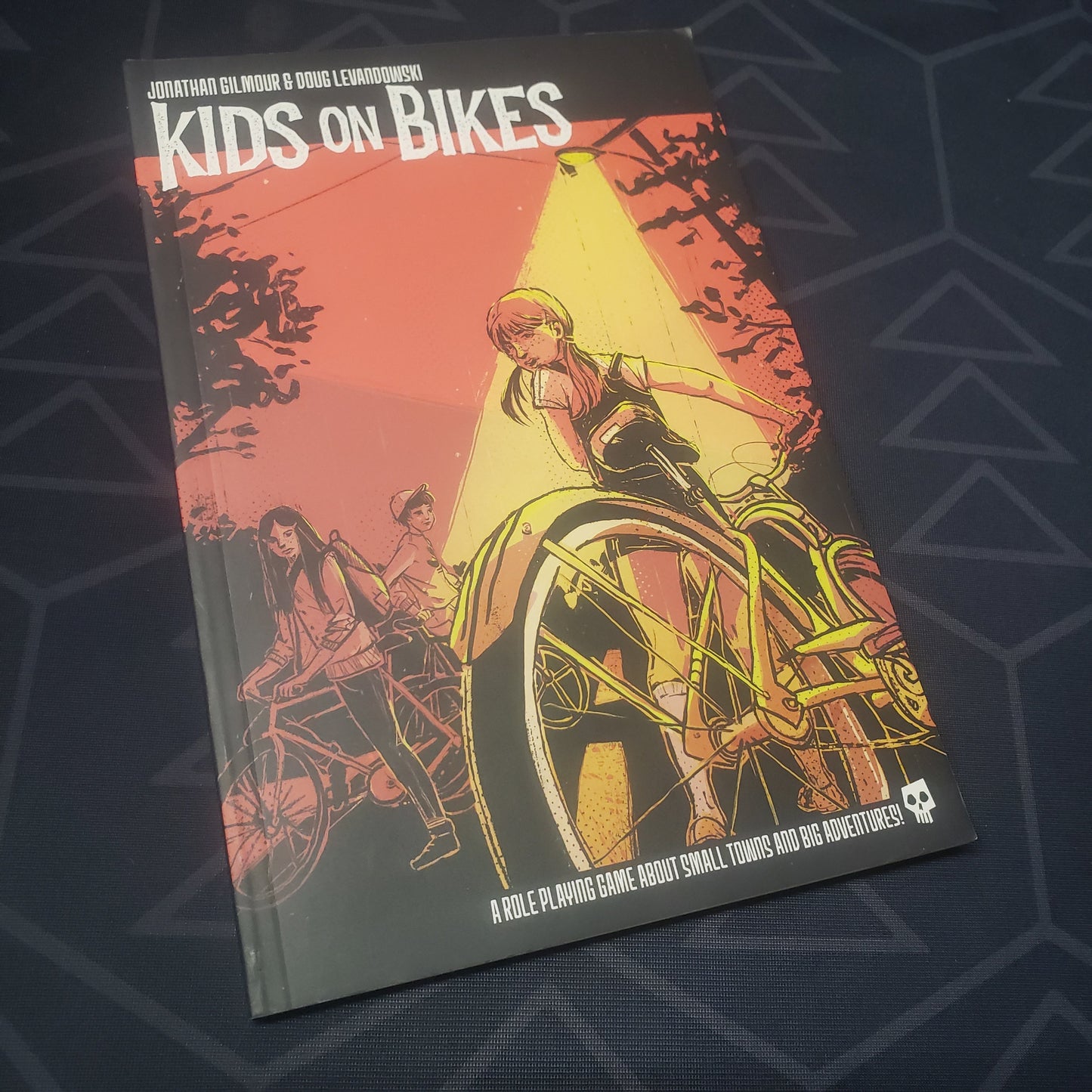 Image shows the front cover of the first edition core rulebook for the roleplaying game Kids on Bikes