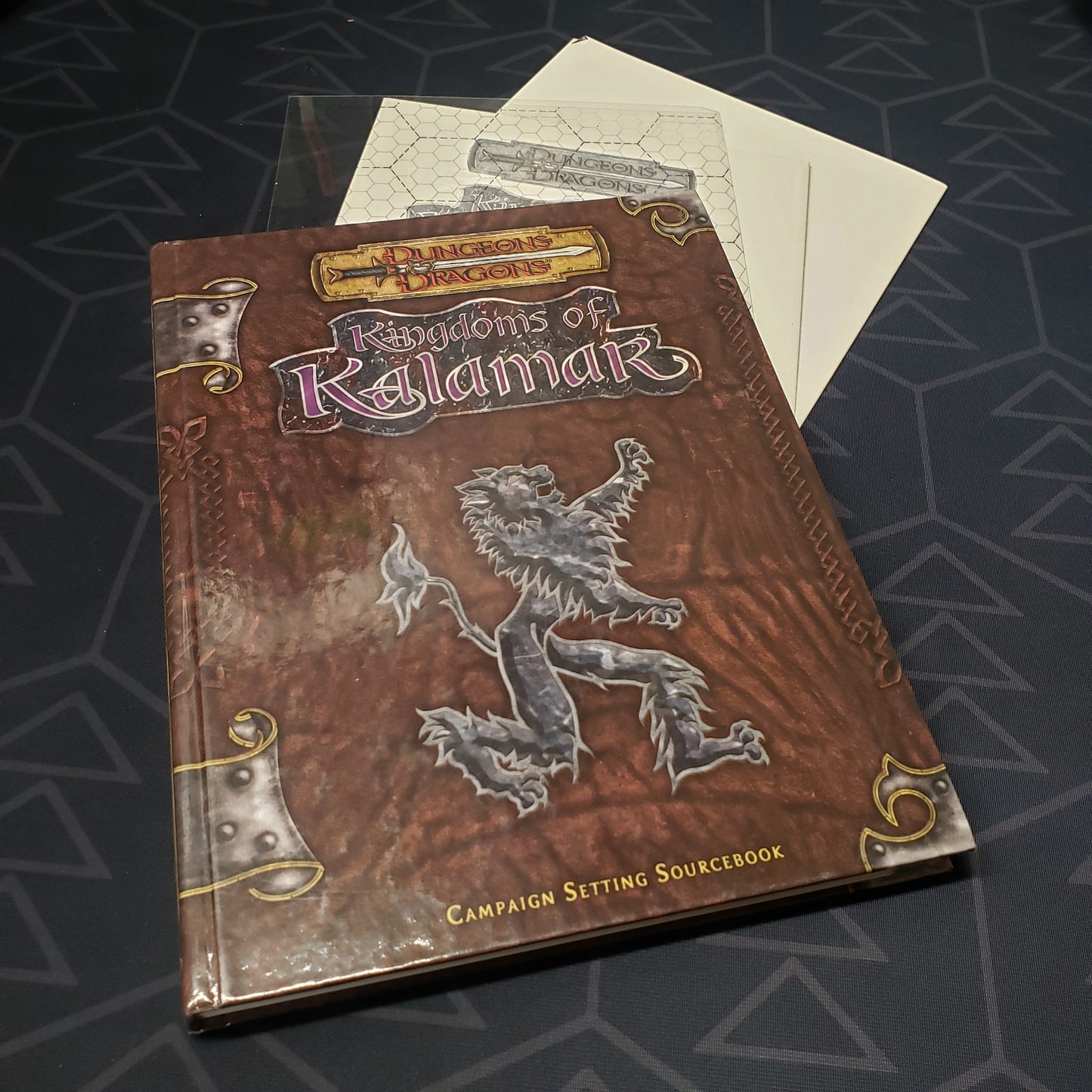 Image shows the front cover of the Kingdoms of Kalamar: Campaign Setting roleplaying game book with the map and transparency inserts fanned out