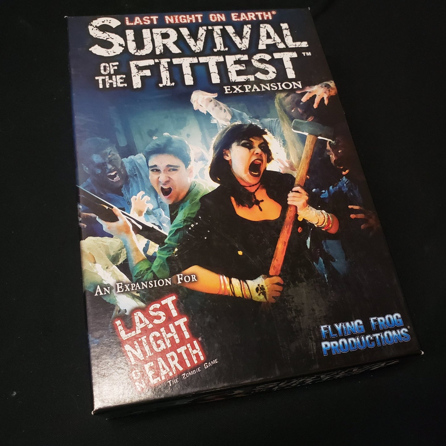 Image shows the front cover of the box of the Survival of the Fittest expansion for the board game Last Night on Earth