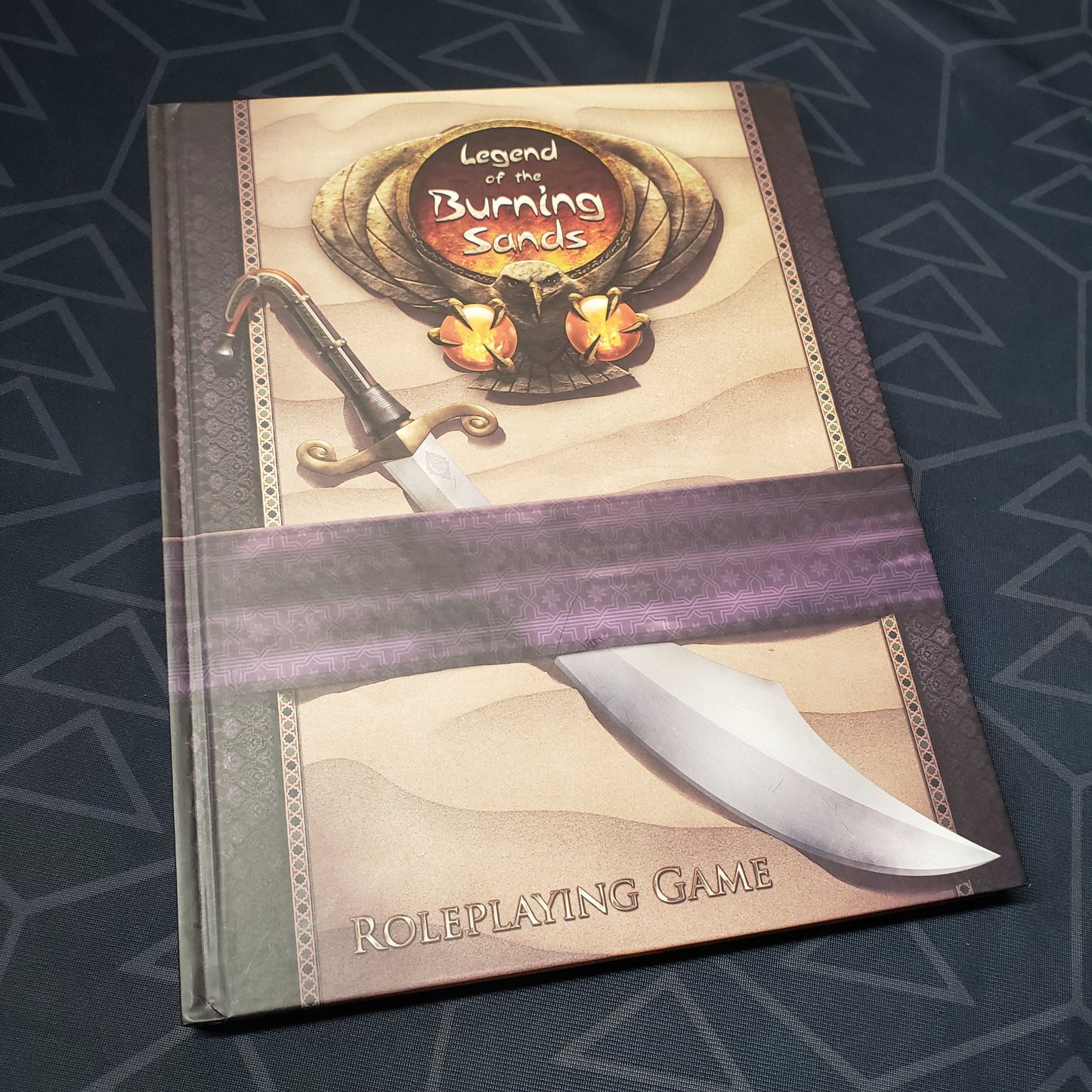 Image shows the front cover of the core rulebook for the roleplaying game Legend of the Burning Sands
