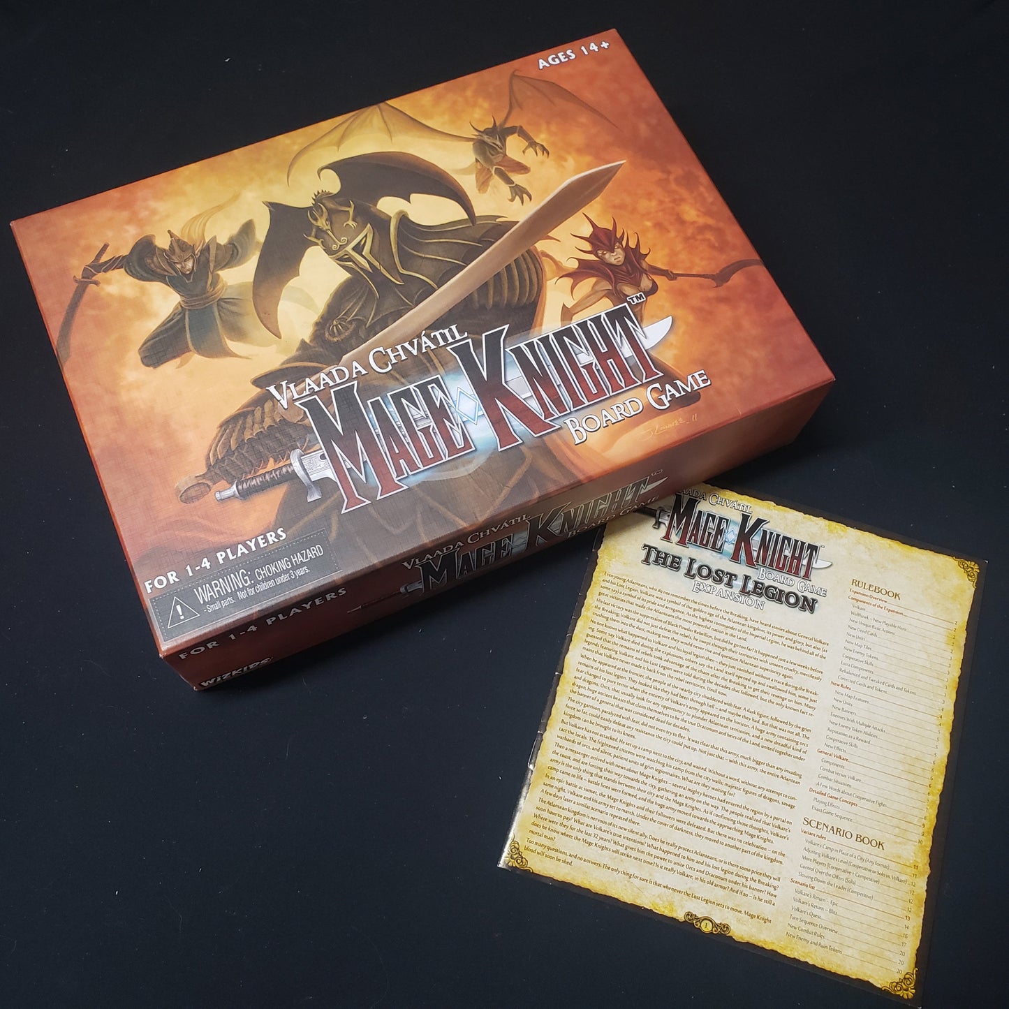 Image shows the front cover of the box for the Mage Knight Board Game with the instructions for the Lost Legion expansion sitting next to it