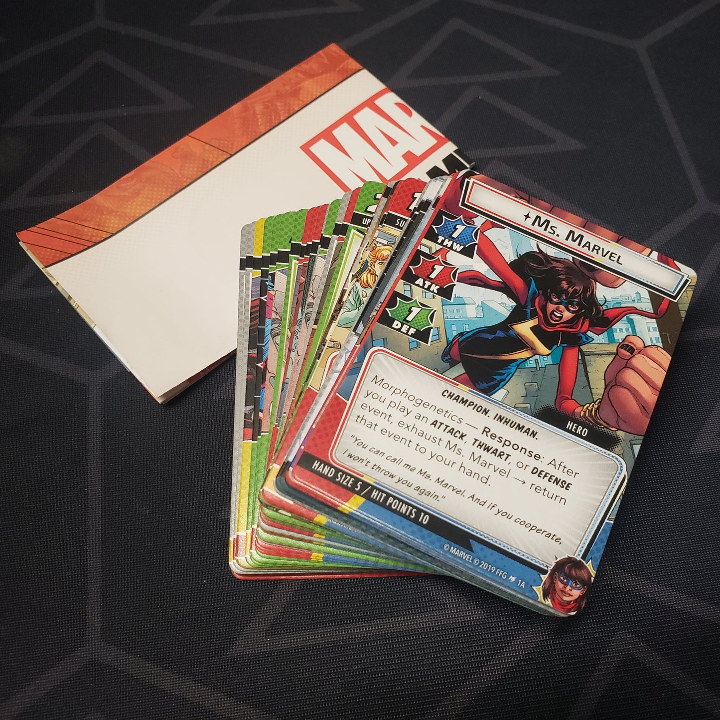 Image shows the instructions & cards fanned-out in a stack for the Ms. Marvel Hero Pack from the Marvel Champions card game
