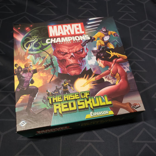 Image shows the front cover of the box of the Rise of Red Skull expansion for the card game Marvel Champions