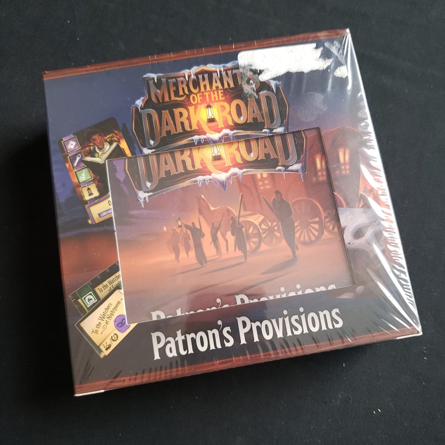 Image shows the front cover of the box of the Patron's Provision's expansion for the board game Merchants Of The Dark Road