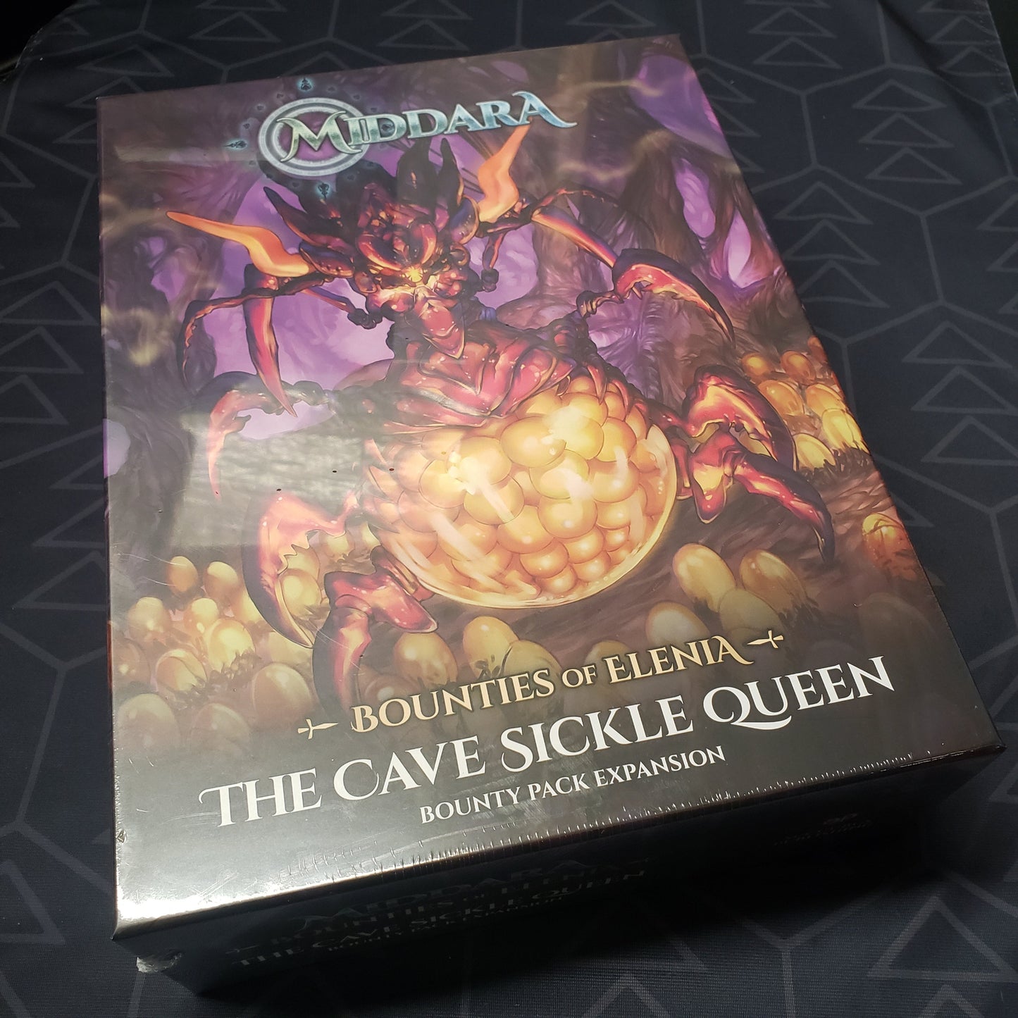 Image shows the front cover of the box of the Bounties of Elenia: The Cave Sickle Queen Bounty Pack expansion for the board game Middara