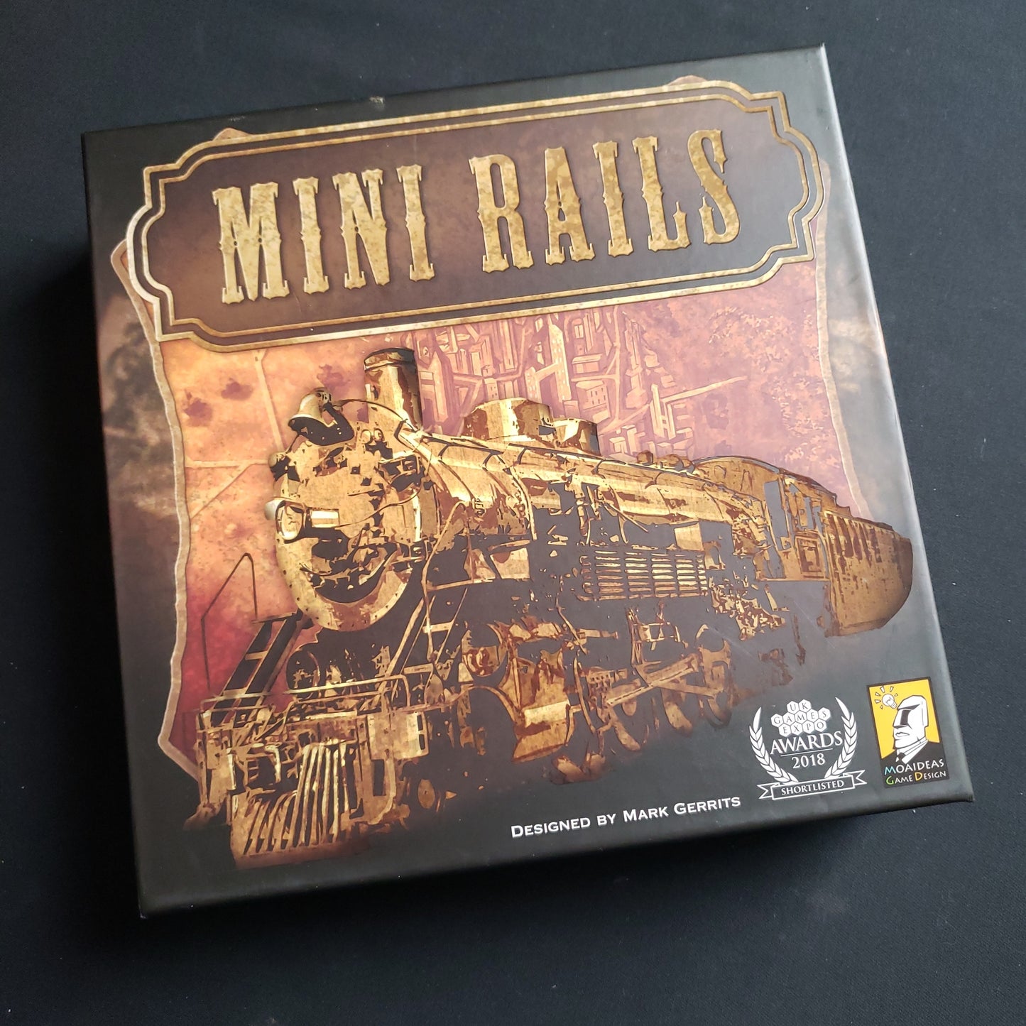 Image shows the front cover of the box of the Mini Rails board game