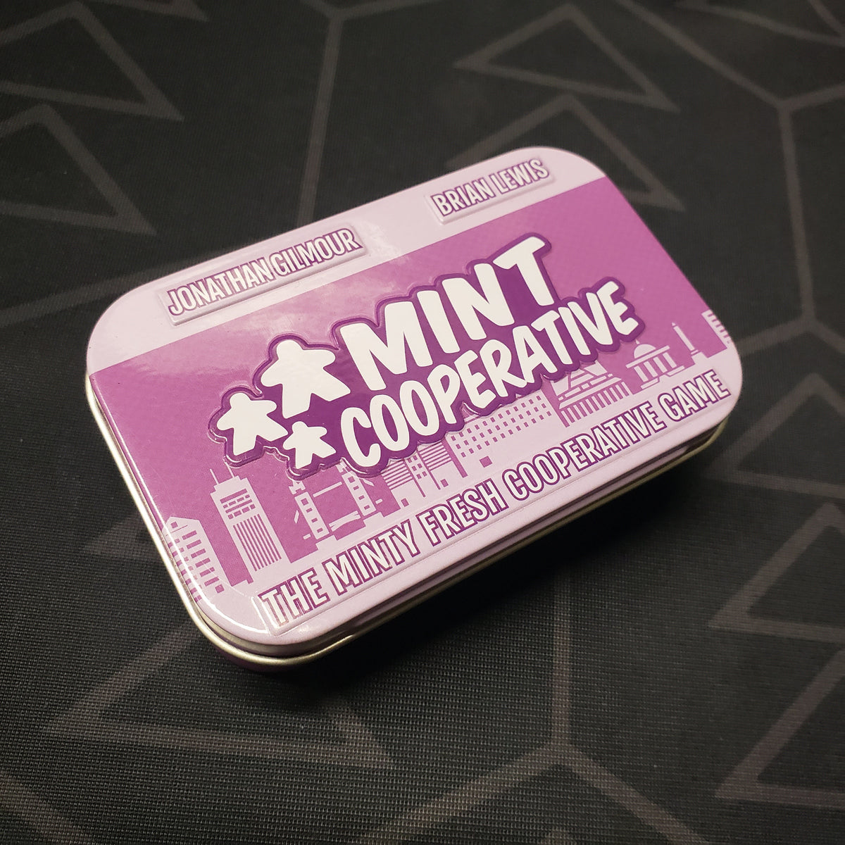 Image shows the front cover of the tin for the Mint Cooperative board game