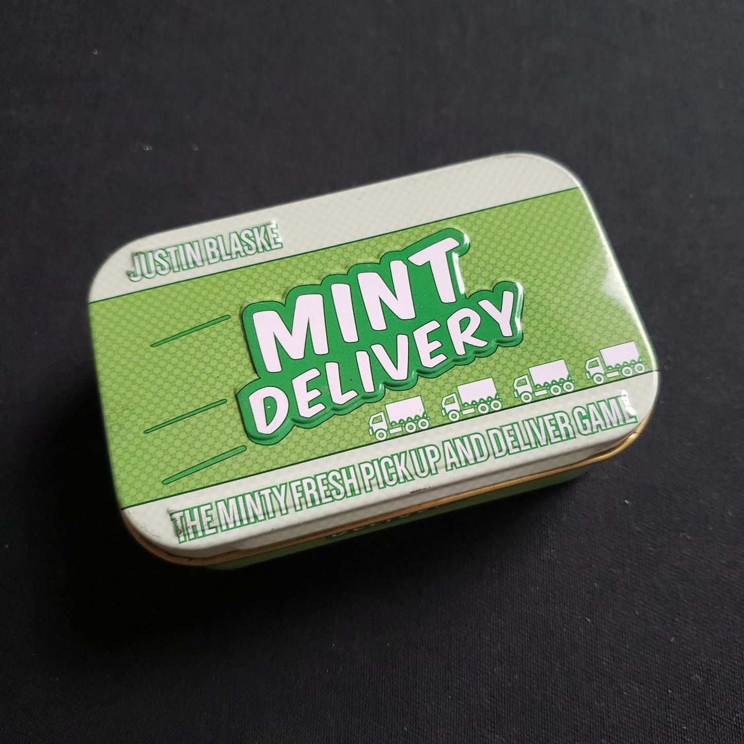 Image shows the front cover of the box of the Mint Delivery board game