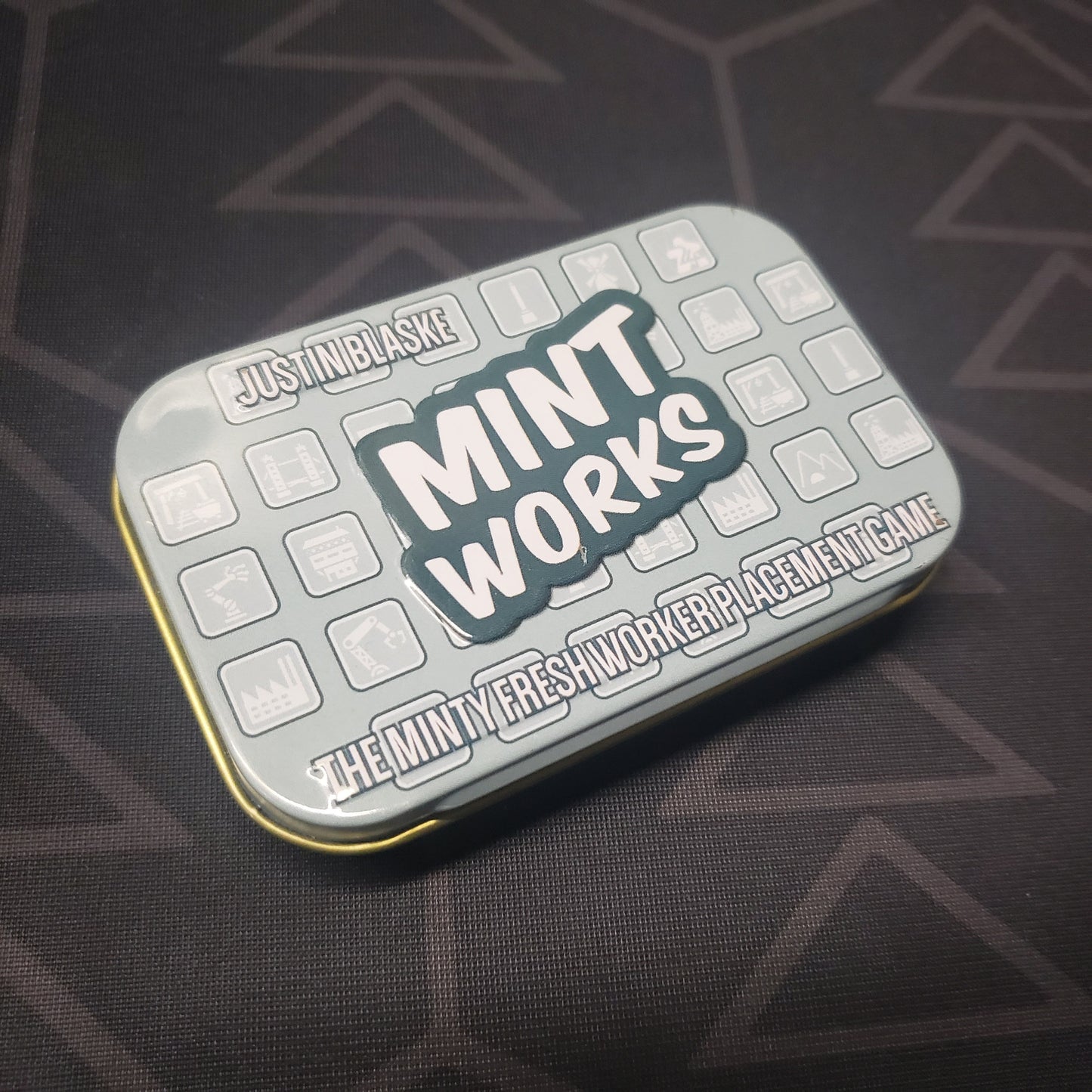 Image shows the front cover of the box for the Mint Works board game