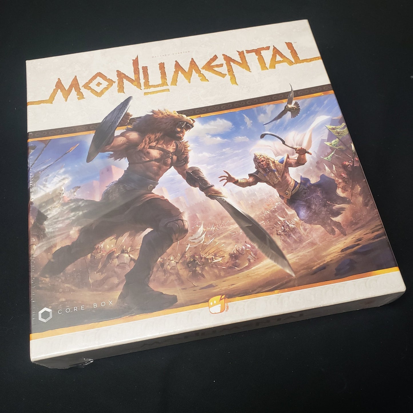 Image shows the front cover of the box of the Monumental board game
