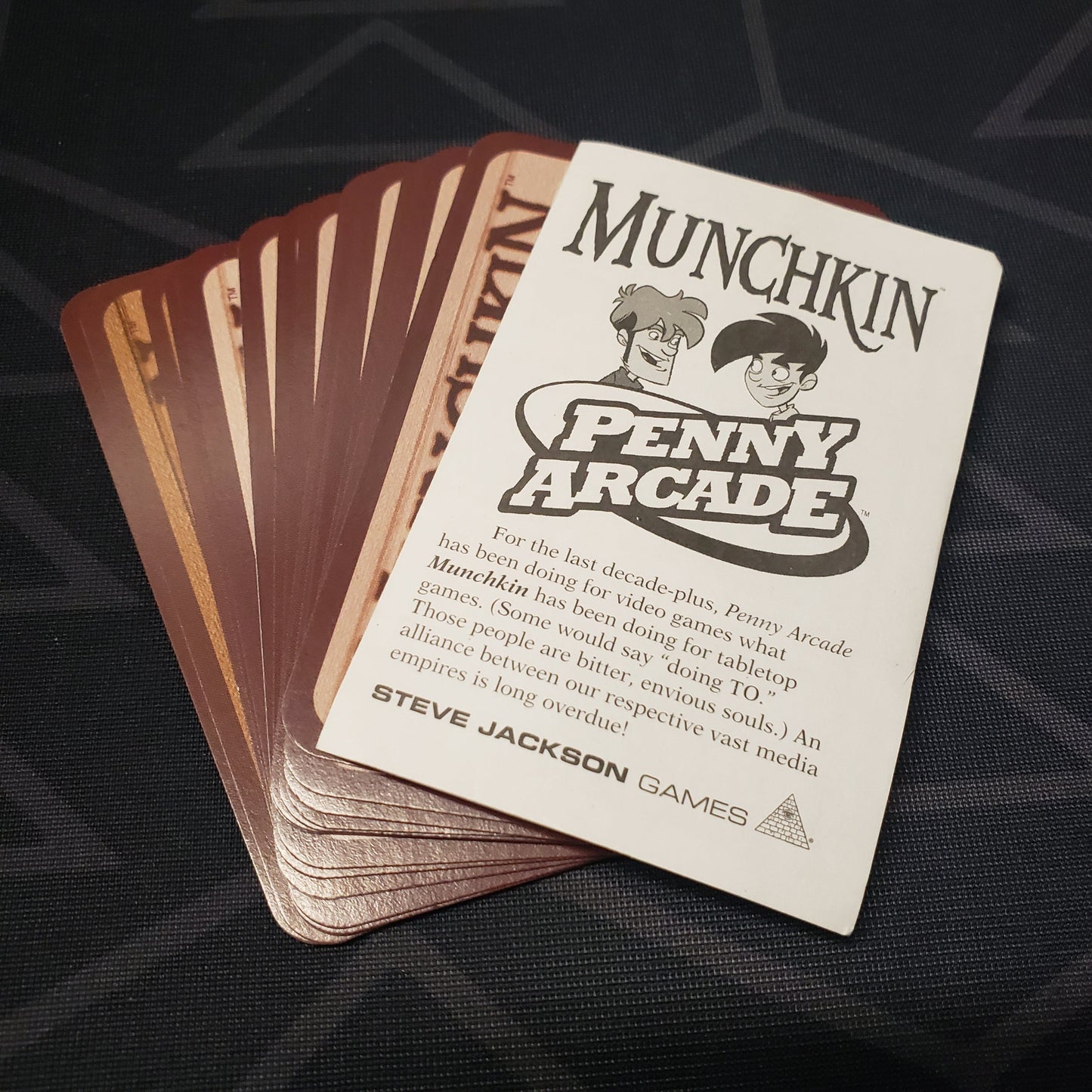 Image shows the instructions & fanned-out cards for the Penny Arcade expansion for the card game Munchkin