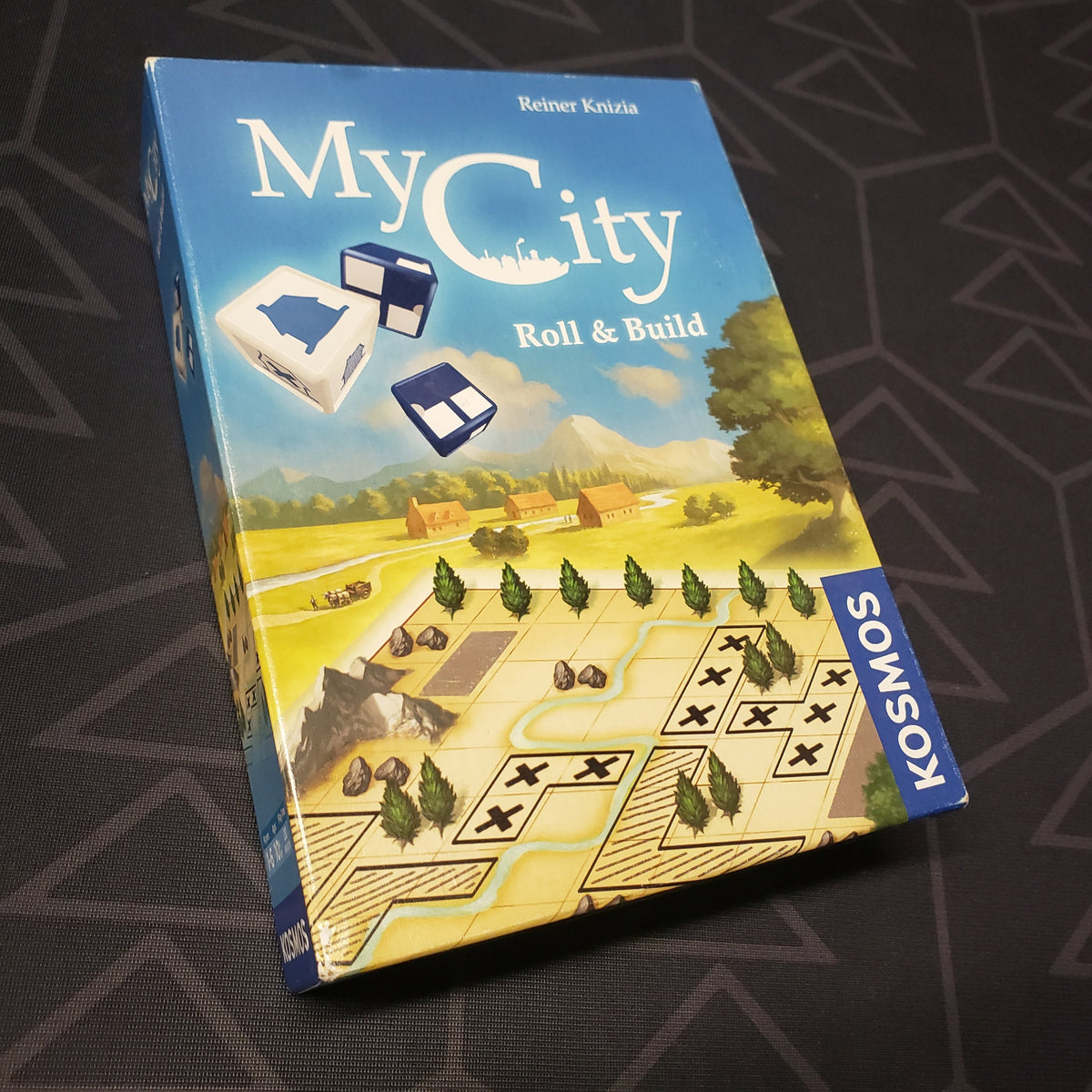 Image shows the front cover of the box of the My City: Roll & Build board game