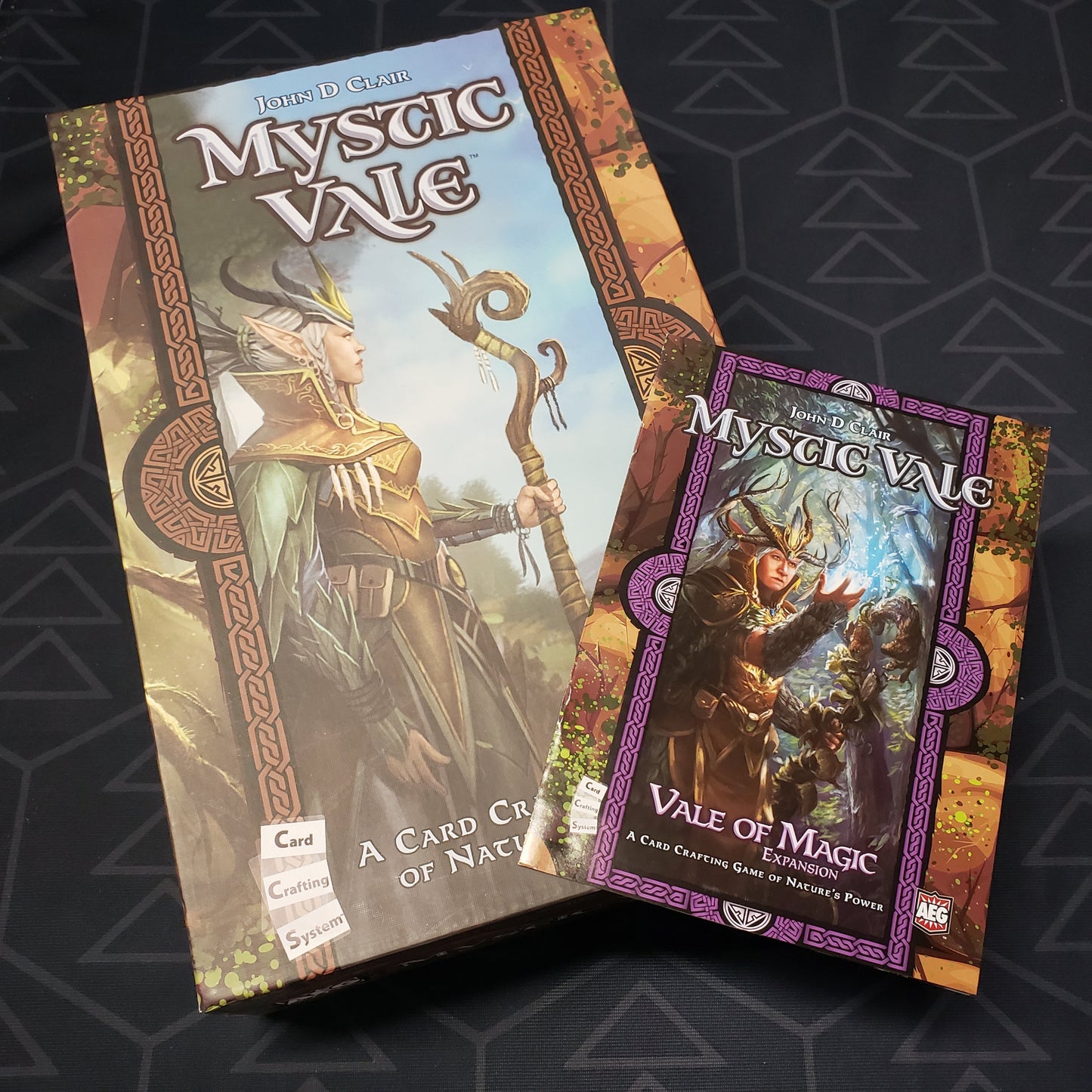 Image shows the front cover of the box of the Mystic Vale board game with the instructions for the Vale of Magic expansion sitting on top of it