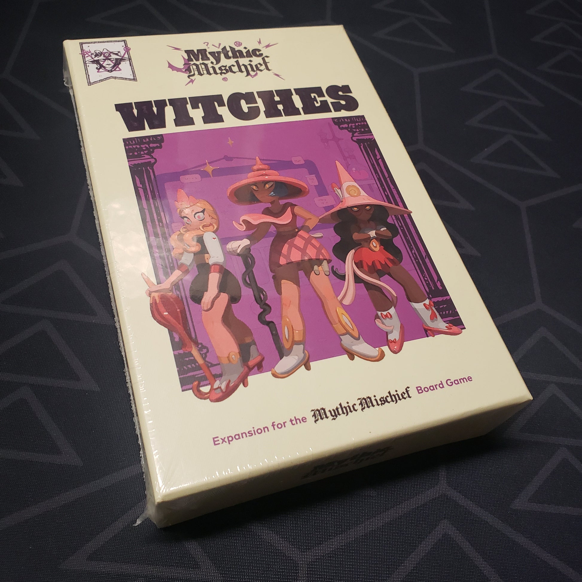 Image shows the front cover of the box of the Witches expansion for the board game Mythic Mischief