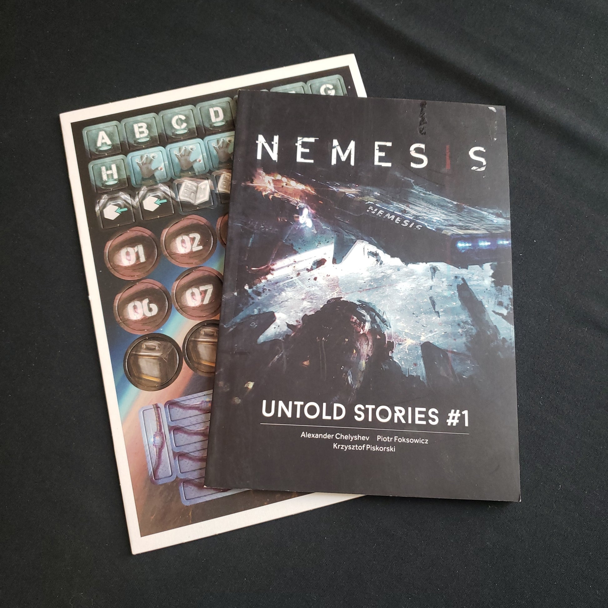 Image shows the front cover of the book and token punchboard for the Untold Stories #1 expansion for the board game Nemesis