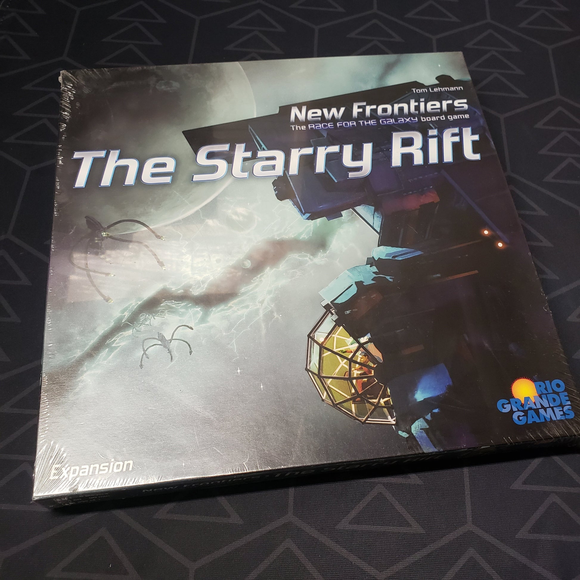 Image shows the front cover of the box of the Starry Rift expansion for the board game New Frontiers