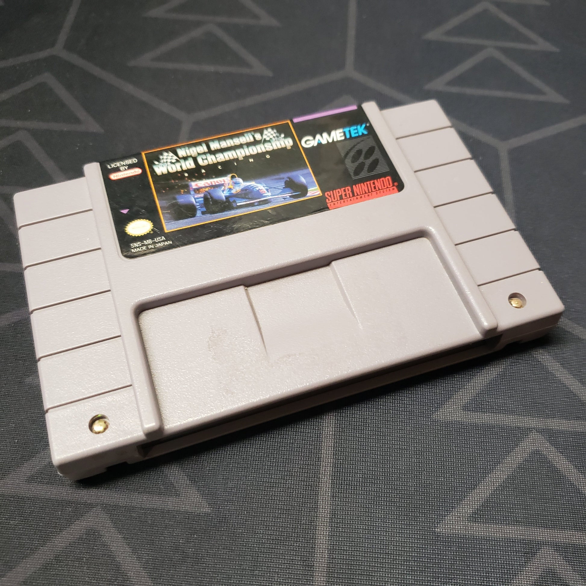 Image shows the front of the cartridge for the video game Nigel Mansell's World Championship Racing for the Super Nintendo