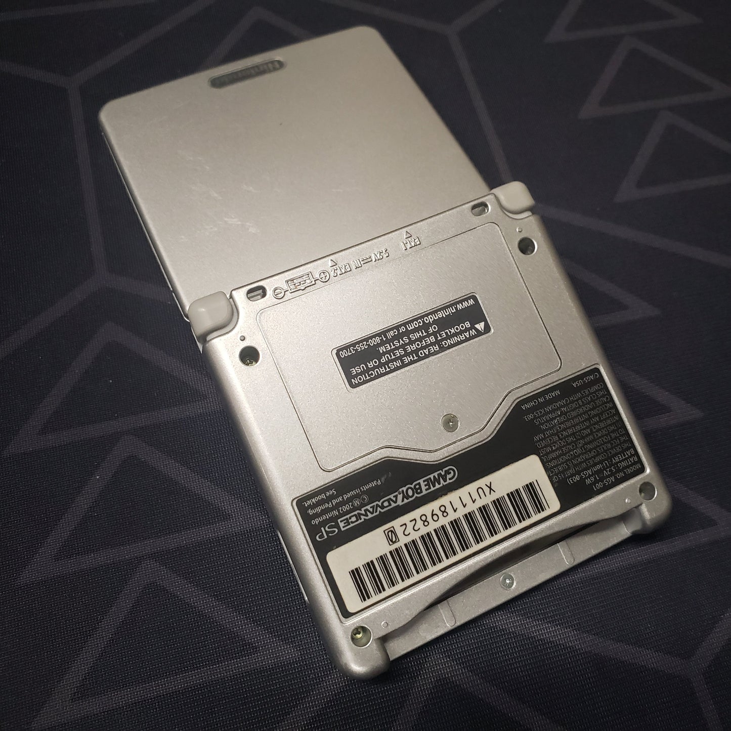 Image shows the back of a platinum Nintendo Game Boy Advance SP gaming console