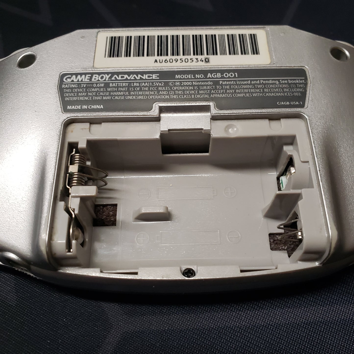 Image shows the back of a Game Boy Advance handheld console with the battery door removed.