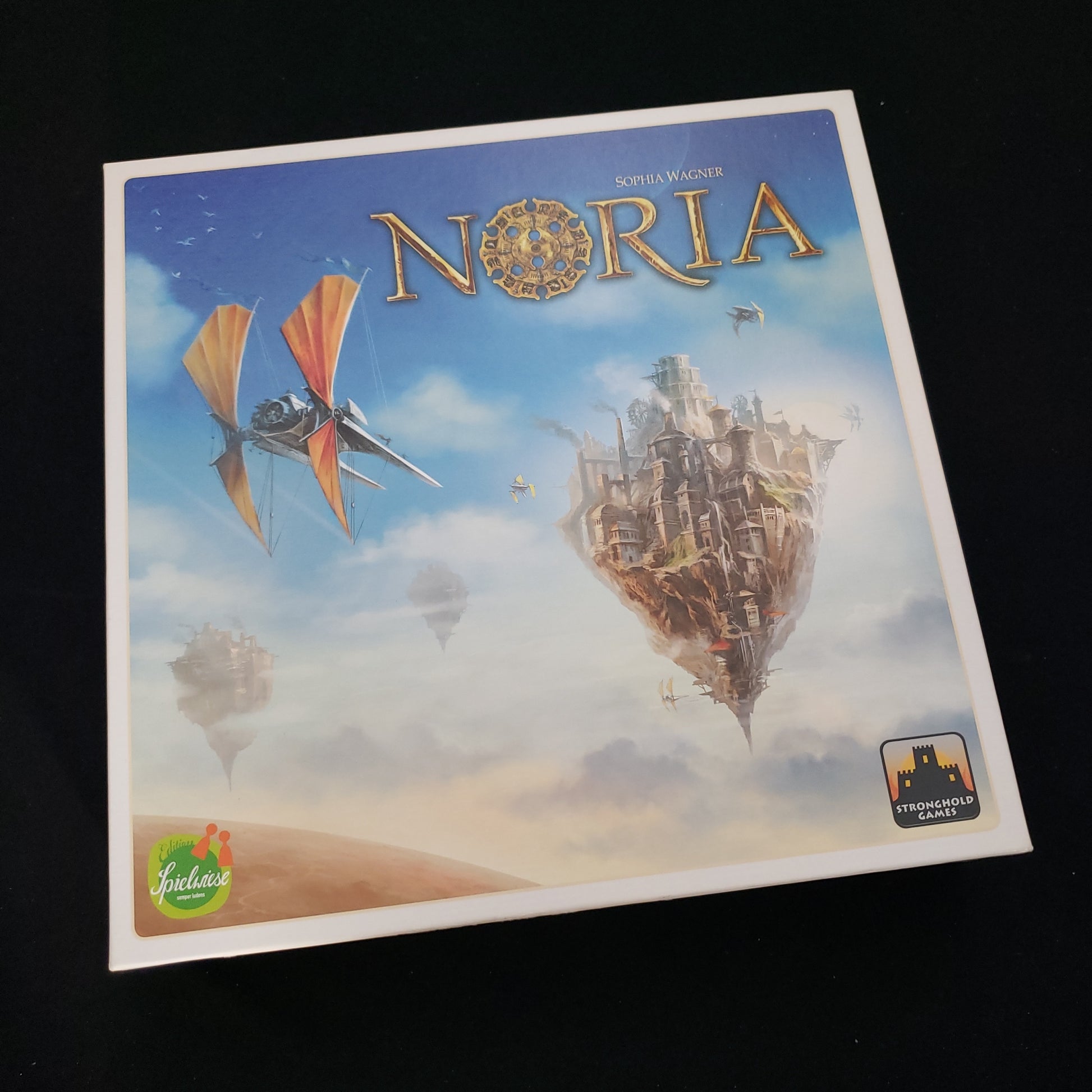 Image shows the front cover of the box of the Noria board game